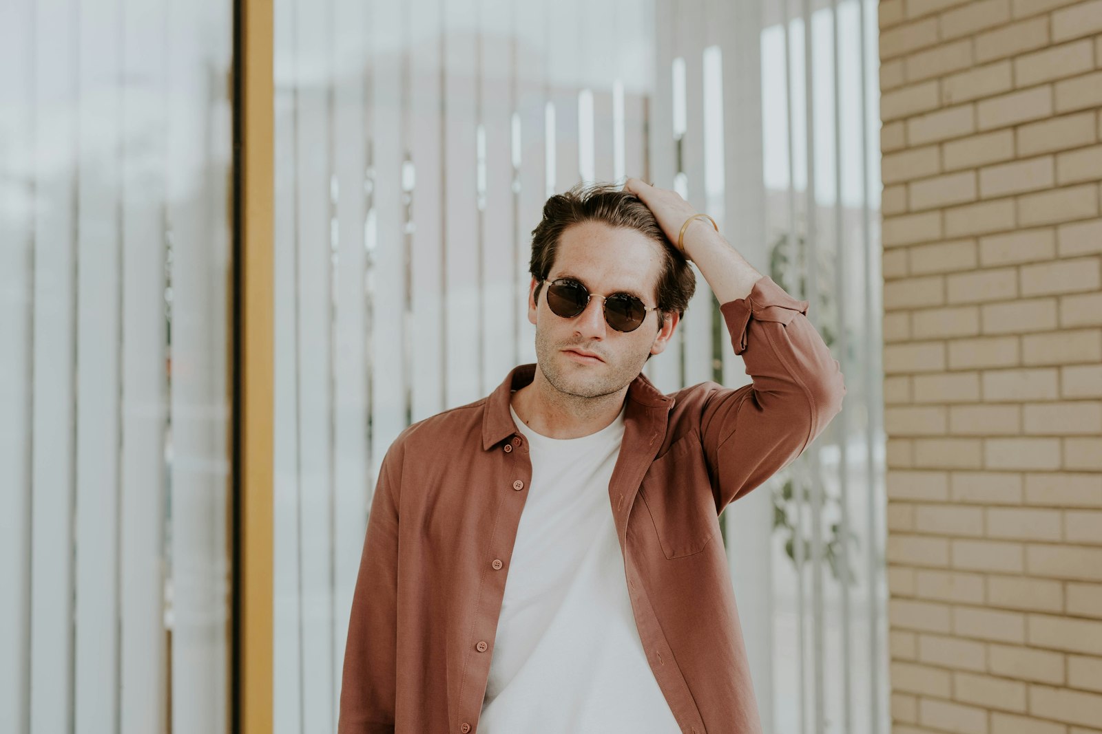 Man in a brown overshirt-style jacket standing by a window