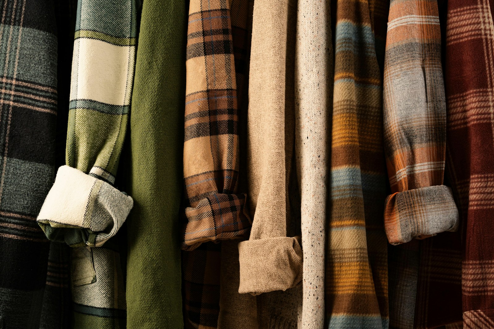Plaid and solid flannel shirts hanging side by side on a rail, how to wear plaid this fall