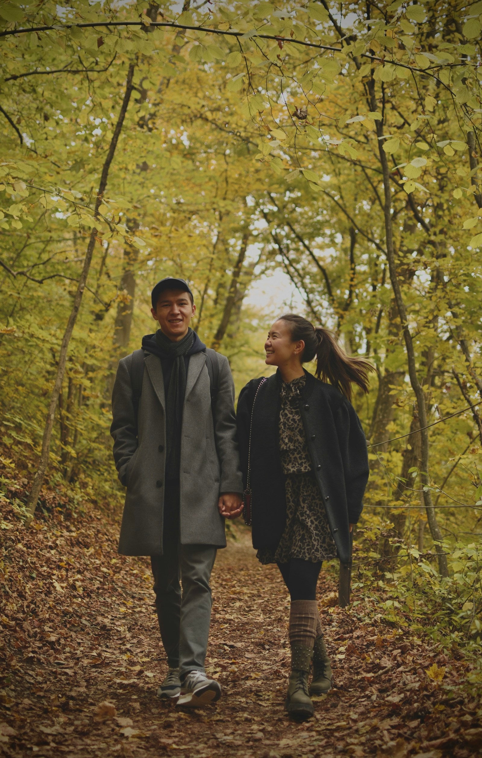 Couple in autumn coats walking through golden woodland