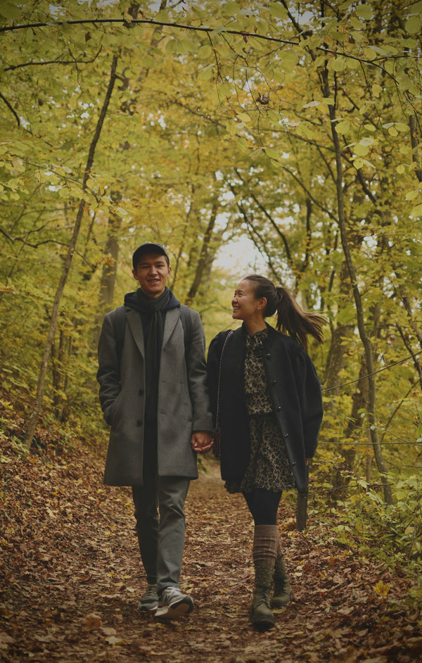 Couple in autumn coats walking through golden woodland