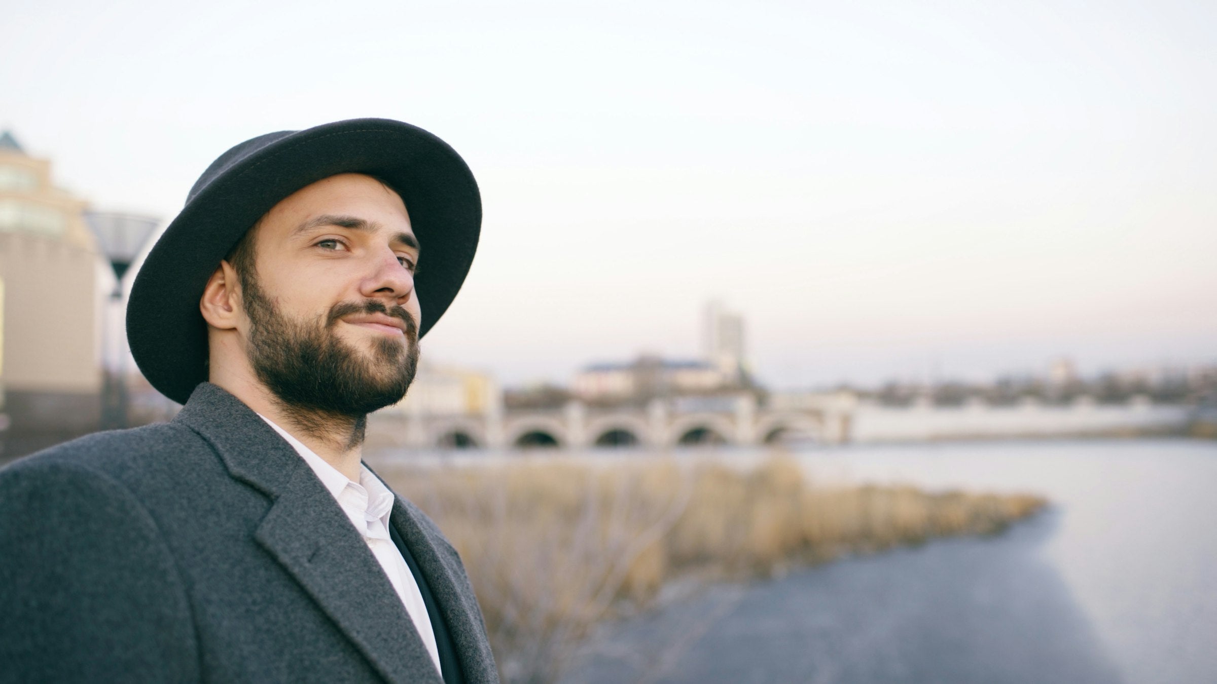 Man in a wool coat and hat on an autumn city riverside
